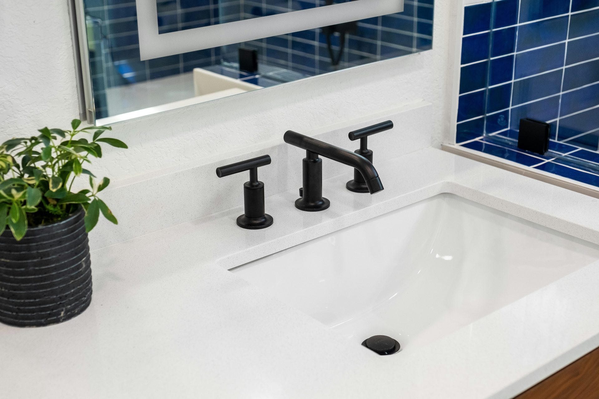 ein Waschbecken mit schwarzer Armatur und einer blau gefliesten Wand